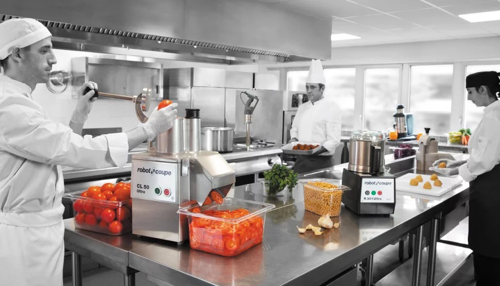 Chef gebruikt een Robot-Coupe groentesnijder in een professionele keuken