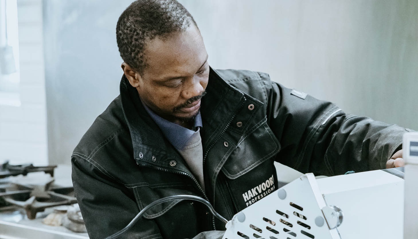 Servicemonteur van Hakvoort Professional installeert apparatuur in een professionele keuken